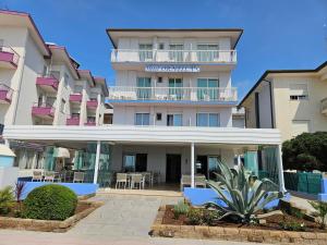 a large apartment building with a patio in front of it at Hotel Ornella in Lido di Jesolo
