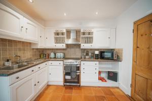 een keuken met witte kasten en een wastafel bij Spacious Heart of town w/garden WiFi Smart TV in Cirencester