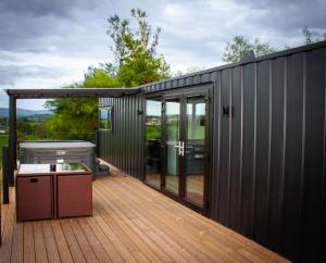 a black house with a deck with a grill at Umry-Calm Farm Stays in Feeny