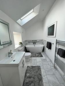 a white bathroom with a tub and a toilet and a sink at The Carthouse (Luxury 2 bed with private hot tub) in Newburgh
