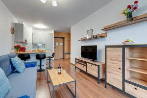 a living room with a blue couch and a kitchen at Apartment Brzeźno Beach by TriApart in Gdańsk