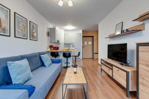 a living room with a blue couch and a table at Apartment Brzeźno Beach by TriApart in Gdańsk