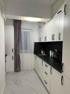 a kitchen with white cabinets and black counter tops at Cozy Studios in Suceava in Suceava
