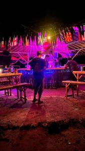 un homme debout devant un bar la nuit dans l'établissement Green smile camping and private beach, à Krabi