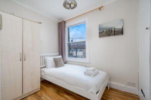 um quarto branco com uma cama e uma janela em Cottage by Cutty Sark, Greenwich em Londres