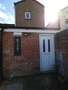 a brick building with a white door and a window at Stylish property near town centre in Tyldesley