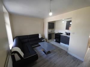 a living room with a black couch and a table at Stylish property near town centre in Tyldesley