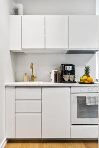 a white kitchen with white cabinets and a sink at Tempus Te Premium Duo Lofts Tartu - private cinema, gym and terrace in Tartu