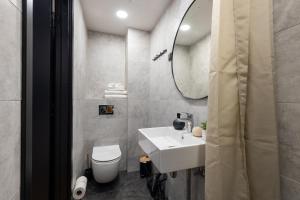 a bathroom with a sink and a toilet and a mirror at Tempus Te Premium Duo Lofts Tartu - private cinema, gym and terrace in Tartu