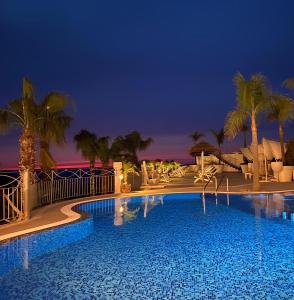 una piscina por la noche con palmeras en Residence Porto Ulisse, en Parghelia