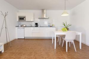 a kitchen with white cabinets and a table and chairs at Peñas Blancas in Mácher