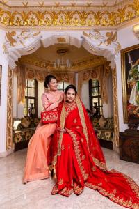 Due donne vestite di rosso sedute in una stanza di Maya Manor Boutique Hotel by KGH Group a Kathmandu