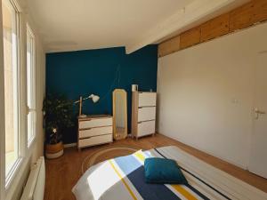 ein Schlafzimmer mit einem Bett und einer blauen Wand in der Unterkunft Maison chaleureuse à Uzès in Uzès