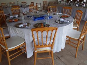 a table with a white table cloth and wooden chairs at Mmelesi Lodge in Maseru