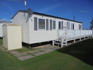a white house with a porch and a fence at Golden Palm : LE Cottage Gold 8 Berth, Panel Heated in Chapel Saint Leonards