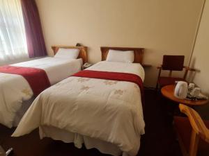 a hotel room with two beds and a table at Mmelesi Lodge in Maseru
