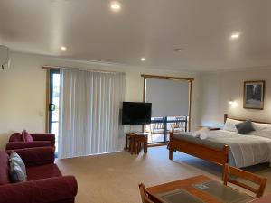 a bedroom with a bed and a couch and a tv at Marsden Court Apartments Now incorporating Marsden Court and Sharonlee Strahan Villas in Strahan