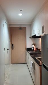 a kitchen with a door leading to a kitchen with white cabinets at The New Villa at Sea Residences in Manila