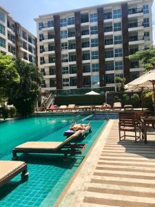 a swimming pool with two people laying on chaises in a building at Diamond Suites Resort in Pattaya South