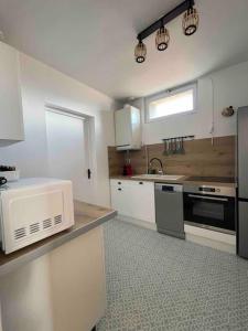 uma cozinha com armários brancos, um lavatório e um micro-ondas em Le vieux Moyrenc em Moirans