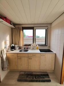 een kleine keuken met een wastafel en een raam bij Woonboot in Sumar gelegen tussen Leeuwarden en Drachten in Suameer