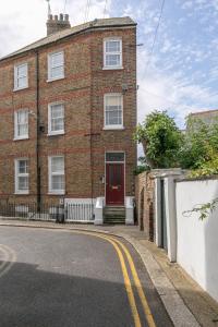 une maison en briques avec une porte rouge dans une rue dans l'établissement Luxury 1BR Broadstairs: 2 mins walk to the beach, à Kent