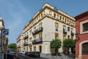 ein großes weißes Gebäude mit Balkon auf einer Straße in der Unterkunft MonKeys Apartments Luxury Puerta de la Maestranza in Sevilla