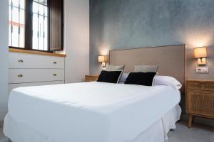ein Schlafzimmer mit einem großen weißen Bett mit zwei Kissen in der Unterkunft MonKeys Apartments Luxury Puerta de la Maestranza in Sevilla