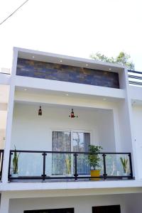 een wit huis met een balkon met 2 potplanten bij Vaishnavam Double Bedroom Villa in Thekkady