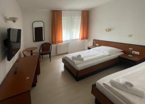 a hotel room with two beds and a television at Hotel am Malerwinkel in Wertheim