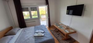 a bedroom with a bed and a table and a television at Guesthouse Buco in Trebinje