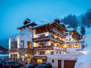 a large building with cars parked in front of it at Burghotel Alpenglühn in Obergurgl