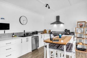 a kitchen with white cabinets and a wooden table at Cabin Getaway in Tathra in Tathra
