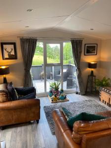 uma sala de estar com dois sofás e uma grande janela em Lovely new caravan by Loch Long em Cove