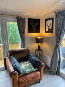 sala de estar con silla de cuero y ventana en Lovely new caravan by Loch Long, en Cove