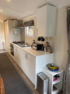 a kitchen with white cabinets and a bowl of bananas on the counter at Lovely new caravan by Loch Long in Cove