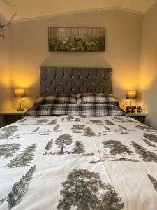 a bedroom with a bed with a bedspread with trees on it at Lovely new caravan by Loch Long in Cove