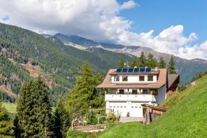 una casa con pannelli solari sul fianco di una collina di Glocklechnhof Sonnenschein a Cadipietra