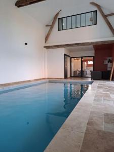 una piscina con acqua blu in un edificio di Gîte du Plantagenêt - Piscine intérieure privative a Rouez
