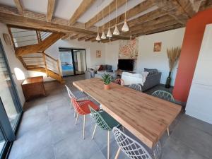 un soggiorno con tavolo e sedie in legno di Gîte du Plantagenêt - Piscine intérieure privative a Rouez