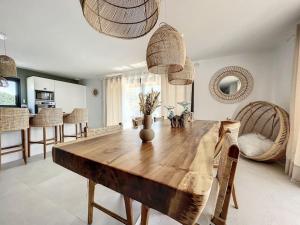 een eetkamer met een houten tafel en stoelen bij Well’Home Bali - Superbe villa au Nord de Toulouse in Mirepoix-sur-Tarn