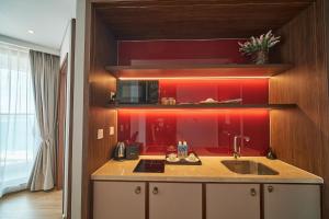 una cucina con lavandino e parete rossa di Apec Mandala Luxury Mui Ne a Mui Ne