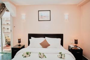 a bedroom with a bed with white sheets and flowers at Hôtel Texuda in Rabat