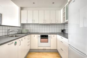 Una cocina blanca con gabinetes blancos y un fregadero. en Amazing Two Bedroom Apartment in Urban Area, en Copenhague