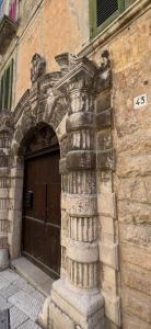 - un bâtiment en pierre avec une porte dotée d'un pilier à l'avant dans l'établissement Il Soprano, à Altamura