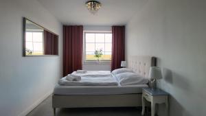 a white bedroom with a bed and a window at Apartamenty Czerwona Stodoła in Kłodzko