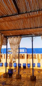 un groupe de chaises bleues sous un toit de paille dans l'établissement maison d'hôtes Le petit jardin Marrakech, à Marrakech