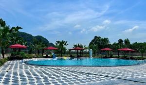 a swimming pool with red umbrellas and a resort at Yen Nhi Hotel Ninh Binh in Ninh Binh