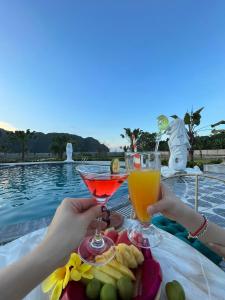 a table with two glasses of drinks next to a pool at Yen Nhi Hotel Ninh Binh in Ninh Binh