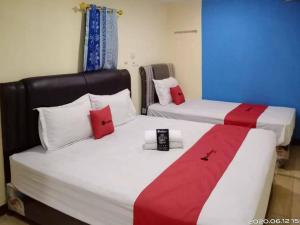 two beds with red and white pillows in a room at RedDoorz At Jalan Japaris Medan in Medan